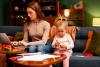 A mother works at a laptop while entertaining a small child