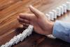Hand stopping a line of dominoes falling