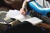Detail of man writing music on an electric guitar
