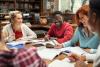 A group of students writing and talking together