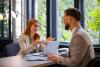 Two people talk over a desk